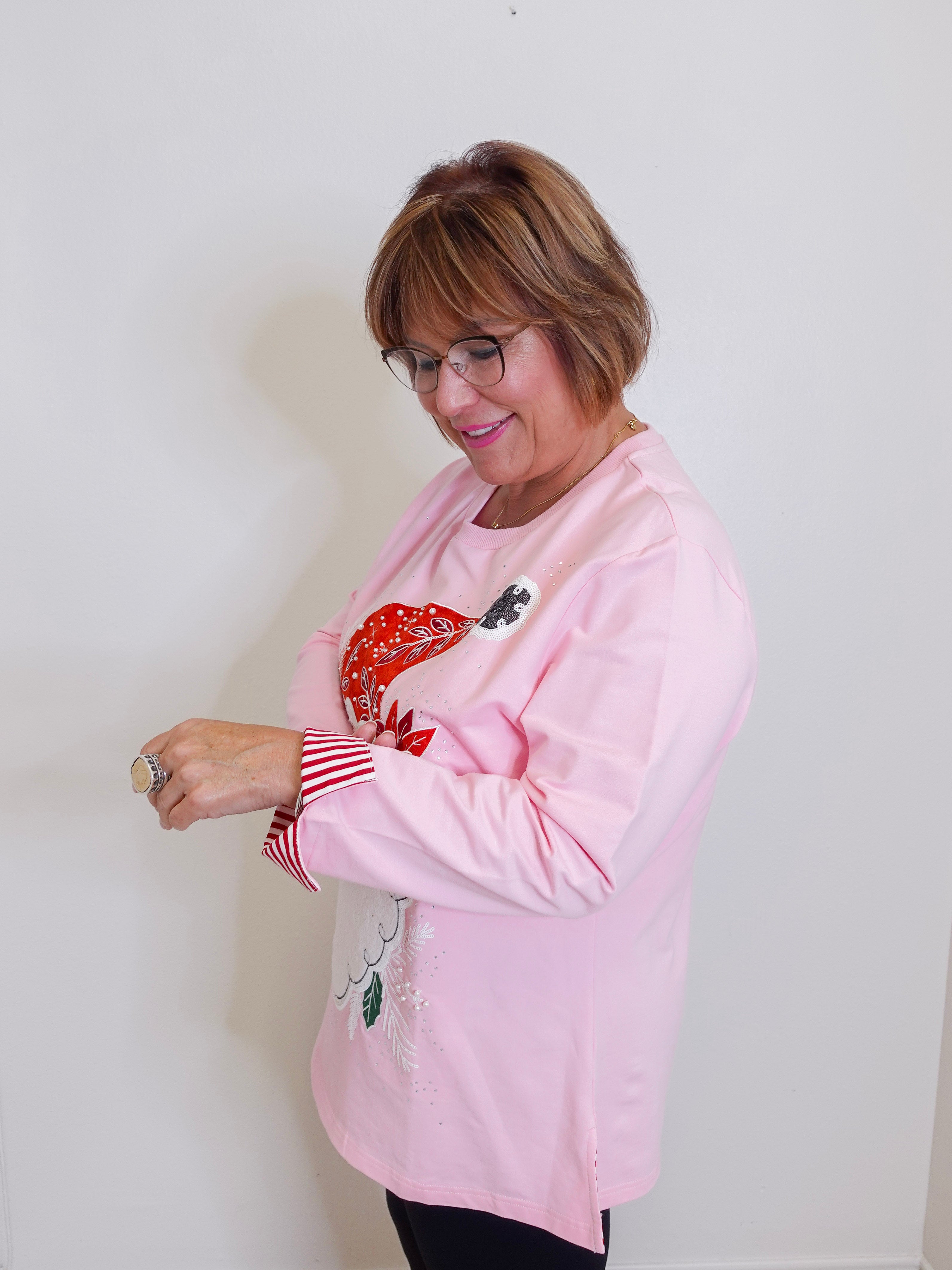 woman wearing a pink Santa baby long sleeve baby sweatshirt against a white background. 