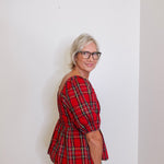 woman wearing a plaid blouse against a white background. 