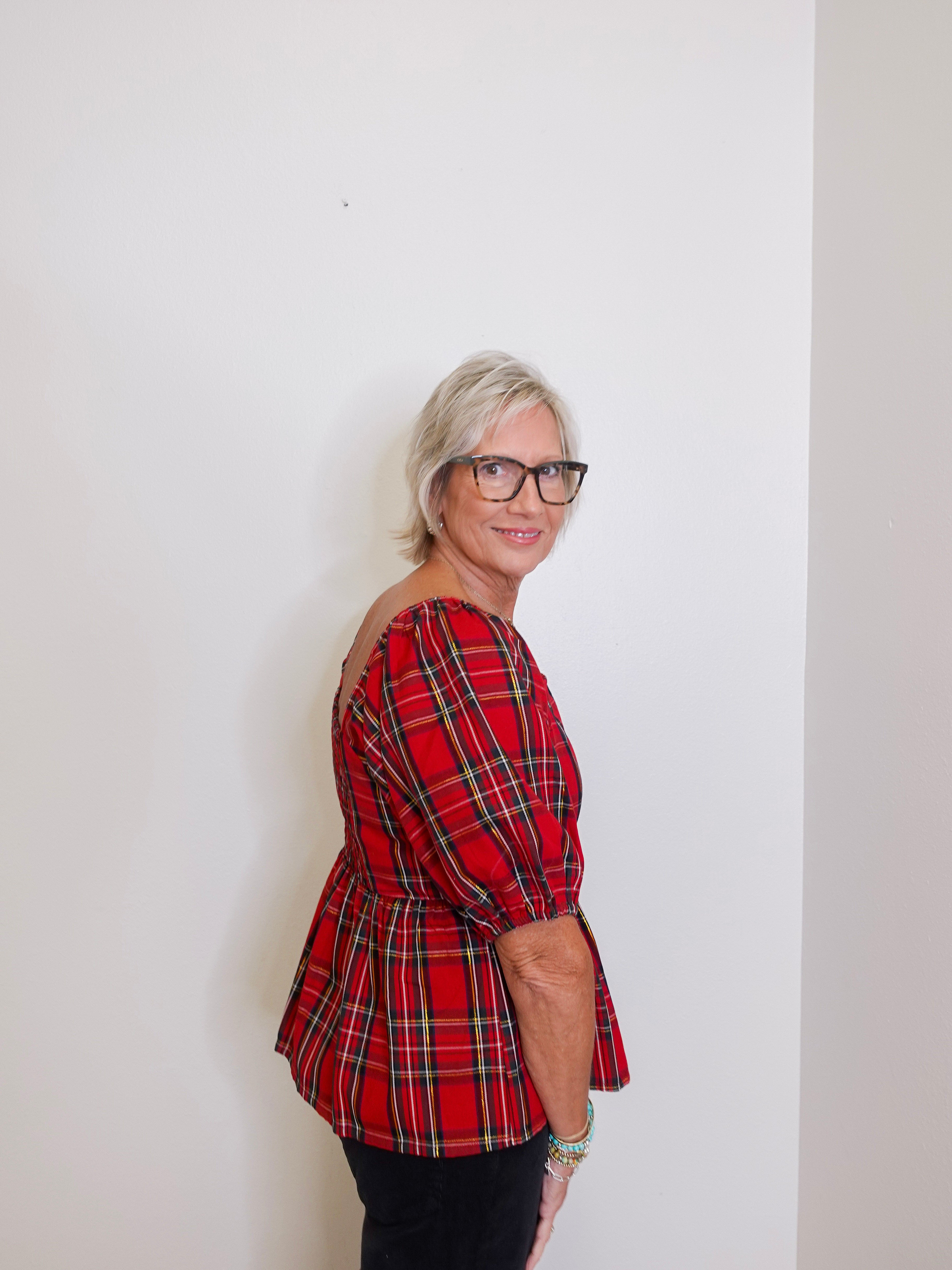 woman wearing a plaid blouse against a white background. 