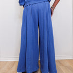 Person wearing a blue outfit with wide-leg pants on a plain background