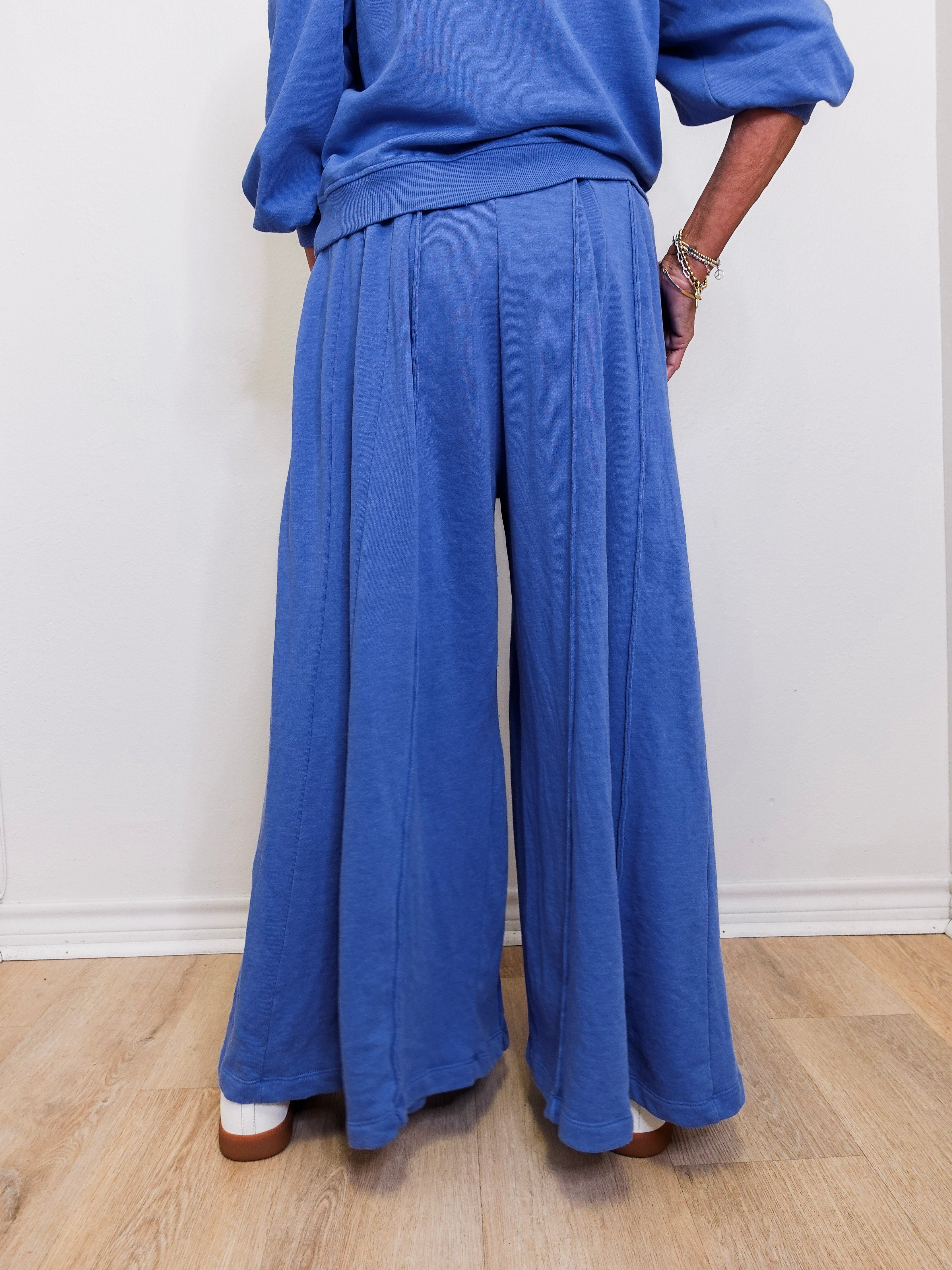 Person wearing a blue outfit with wide-leg pants on a plain background