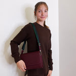 woman wearing consuela plum on the town crossbody-bag against a white background. 