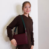 woman wearing consuela plum on the town crossbody-bag against a white background. 