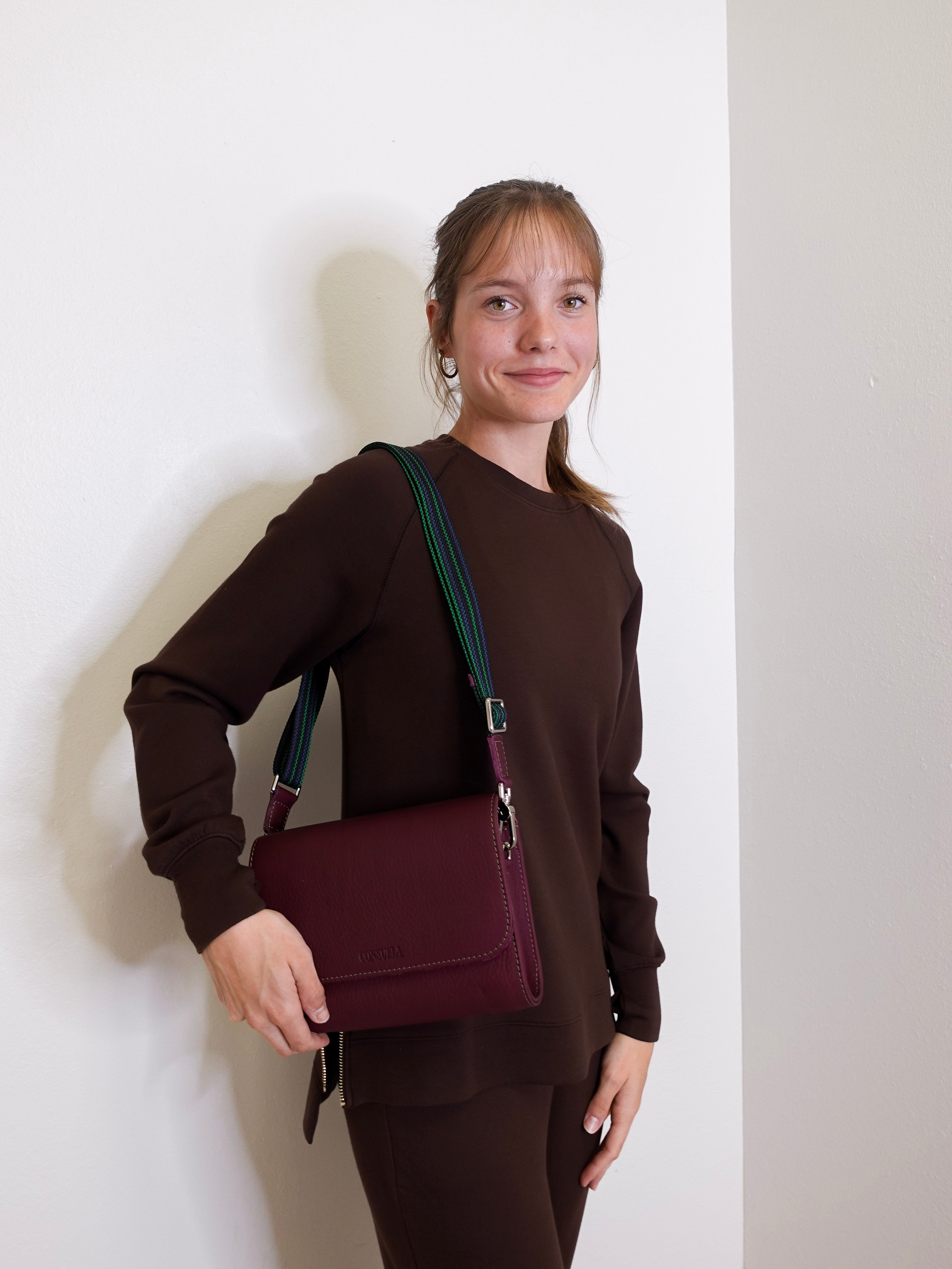 woman wearing consuela plum on the town crossbody-bag against a white background. 