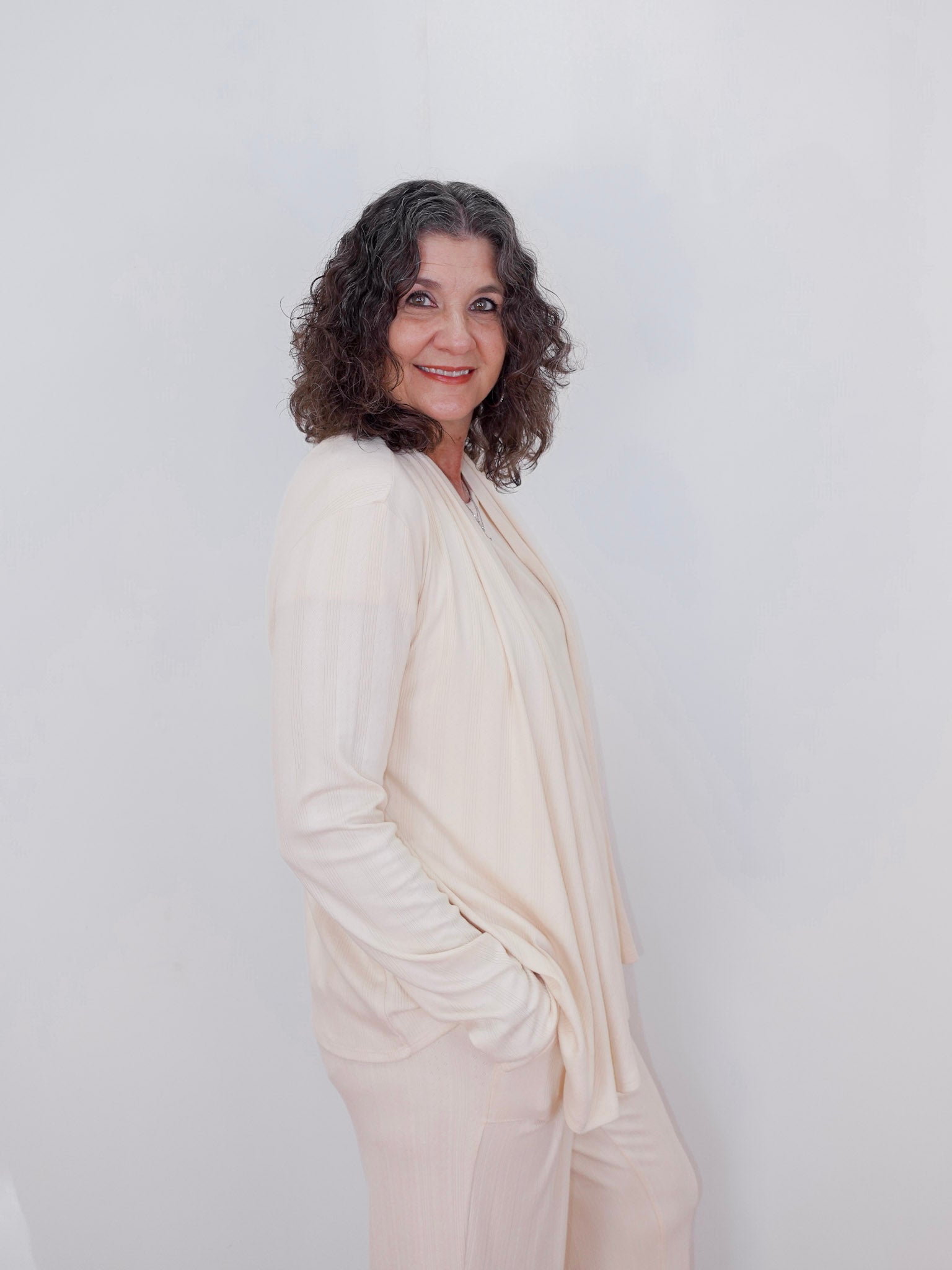 Woman wearing a white outfit against a plain background
