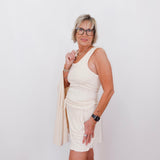 Woman wearing a white dress and beige cardigan against a white background