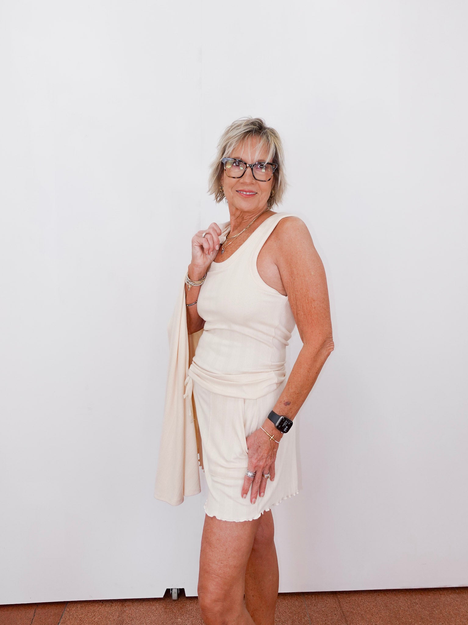 Woman wearing a white dress and beige cardigan against a white background