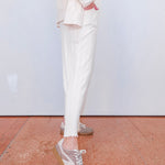 Person wearing white pants and patterned sneakers on a wooden floor.