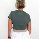 Person wearing a green top and white skirt against a white background