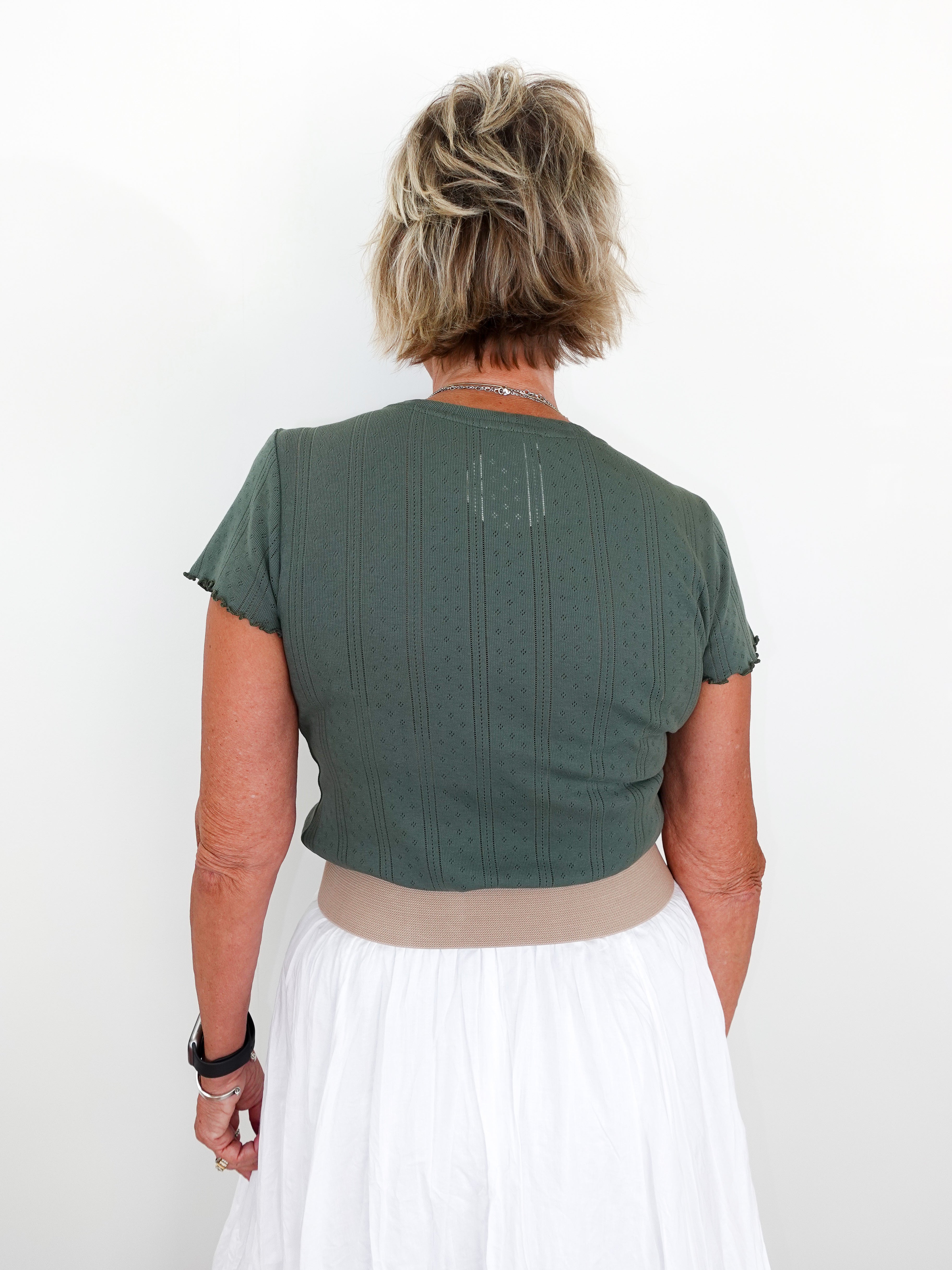 Person wearing a green top and white skirt against a white background