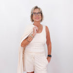 Woman in a white outfit with a beige cardigan against a white background