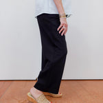 Person wearing black pants and a white shirt with a plain background