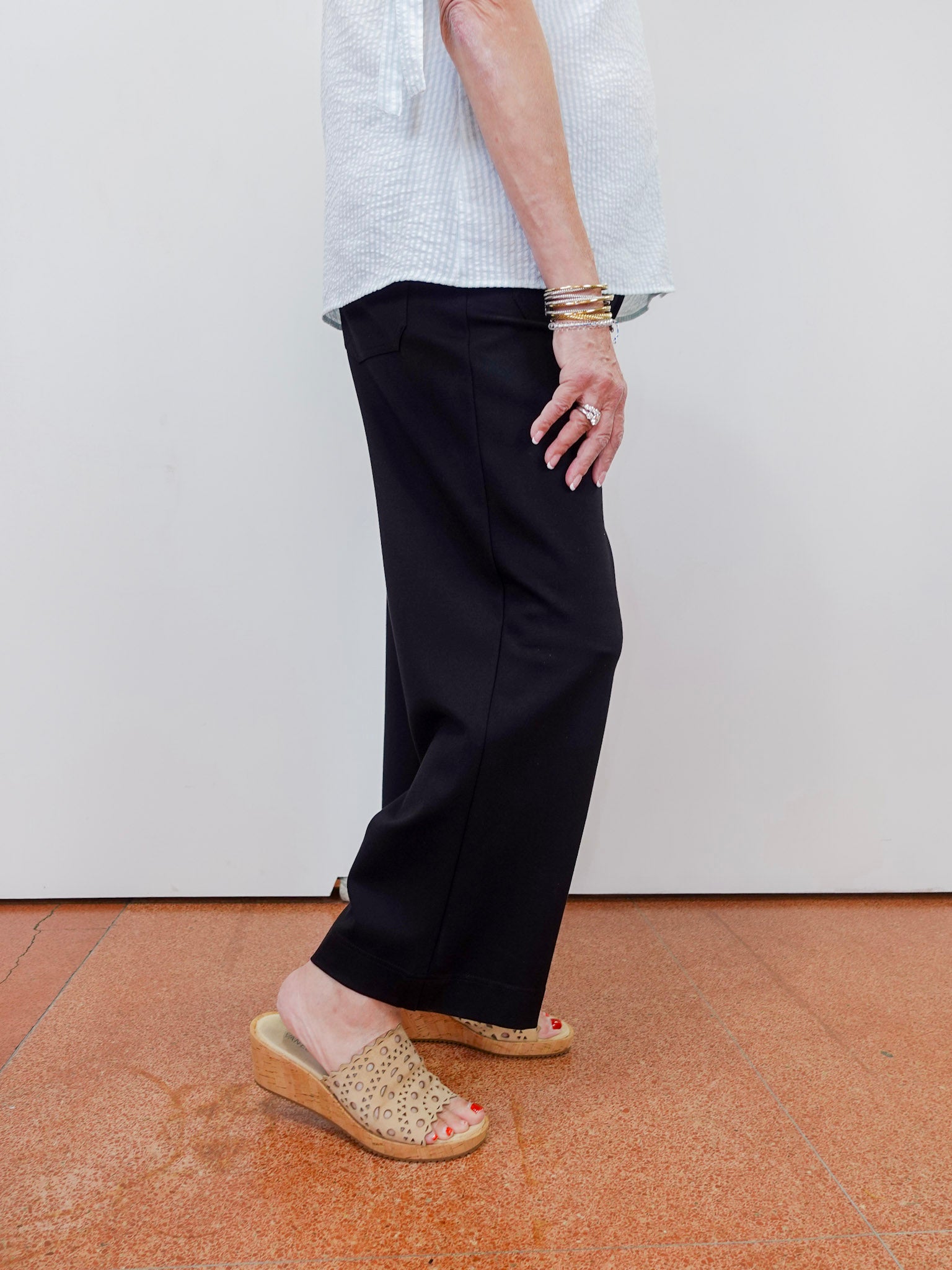 Person wearing black pants and a white shirt with a plain background