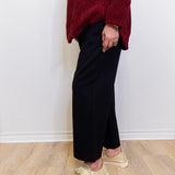 Woman wearing a black wide leg pant against a white background. 