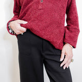 Woman wearing a black pant against a white background. 