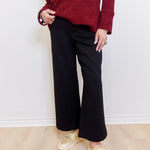 Woman wearing a black cropped wide leg pant against a white background. 