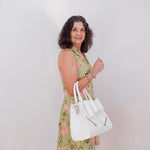 Woman in a green checkered dress holding a white handbag against a plain background