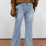 A person shown from the back wearing light-wash blue flare jeans, a brown cropped top with a lace-up back, and carrying a brown shoulder bag against a plain white wall.