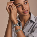 Woman wearing a silver watch and bracelet on a beige background