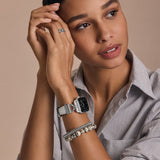 Woman wearing a silver watch and bracelet on a beige background