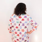 Person wearing a colorful shirt with teacup pattern on a white background