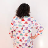 Person wearing a colorful shirt with teacup pattern on a white background