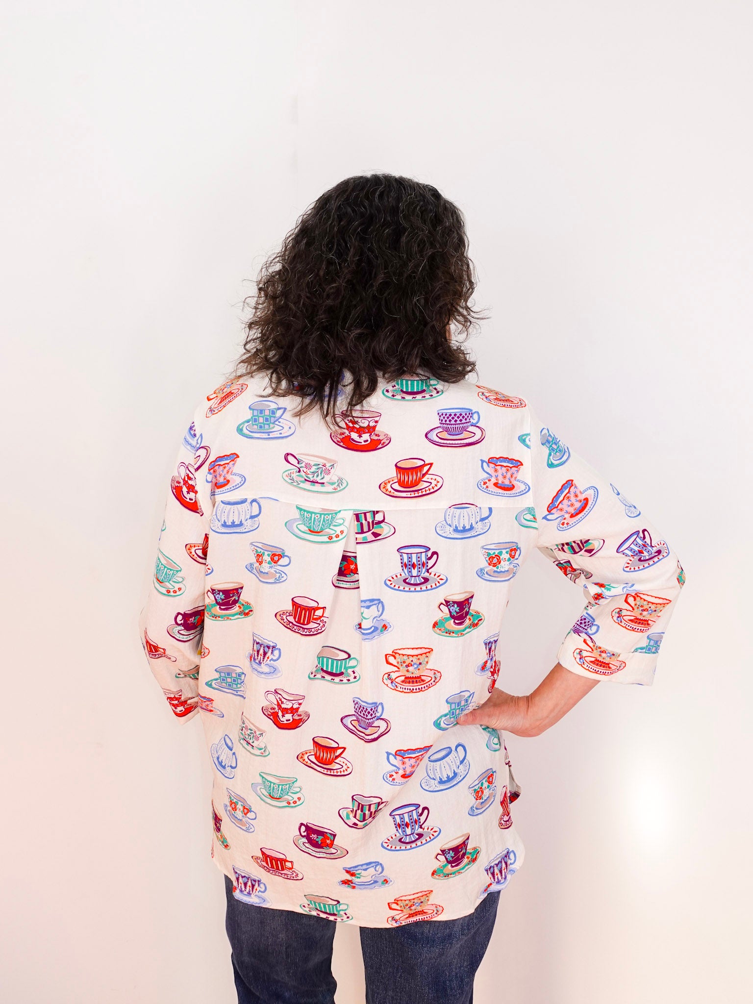 Person wearing a colorful shirt with teacup pattern on a white background