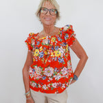 Woman wearing a red floral blouse against a white background