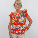 Woman wearing a red floral blouse against a white background
