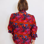 Person wearing a colorful floral blouse against a white background