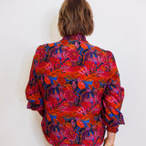 Person wearing a colorful floral blouse against a white background