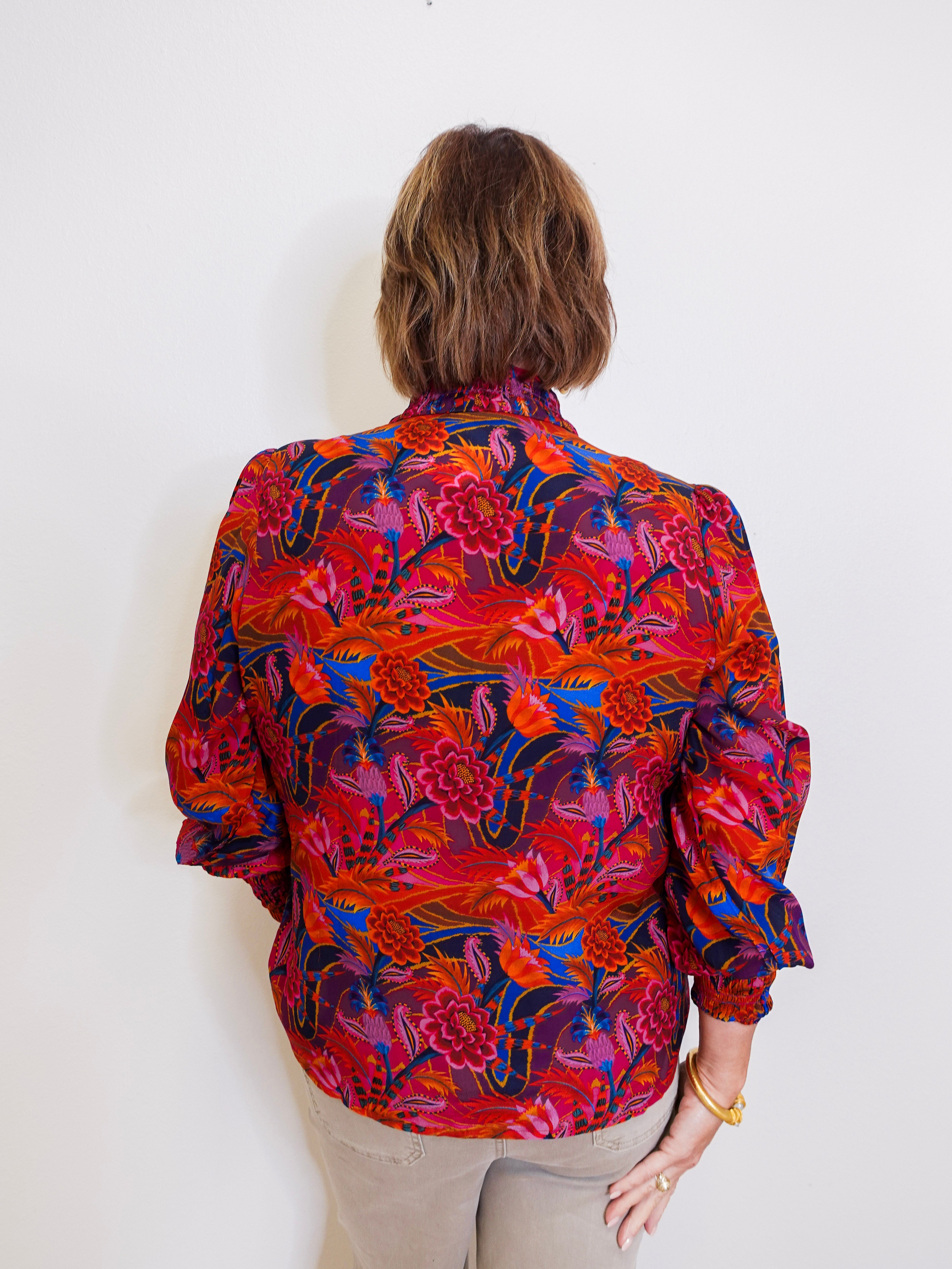 Person wearing a colorful floral blouse against a white background