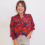 Woman wearing a puff sleeve blouse against a white background.