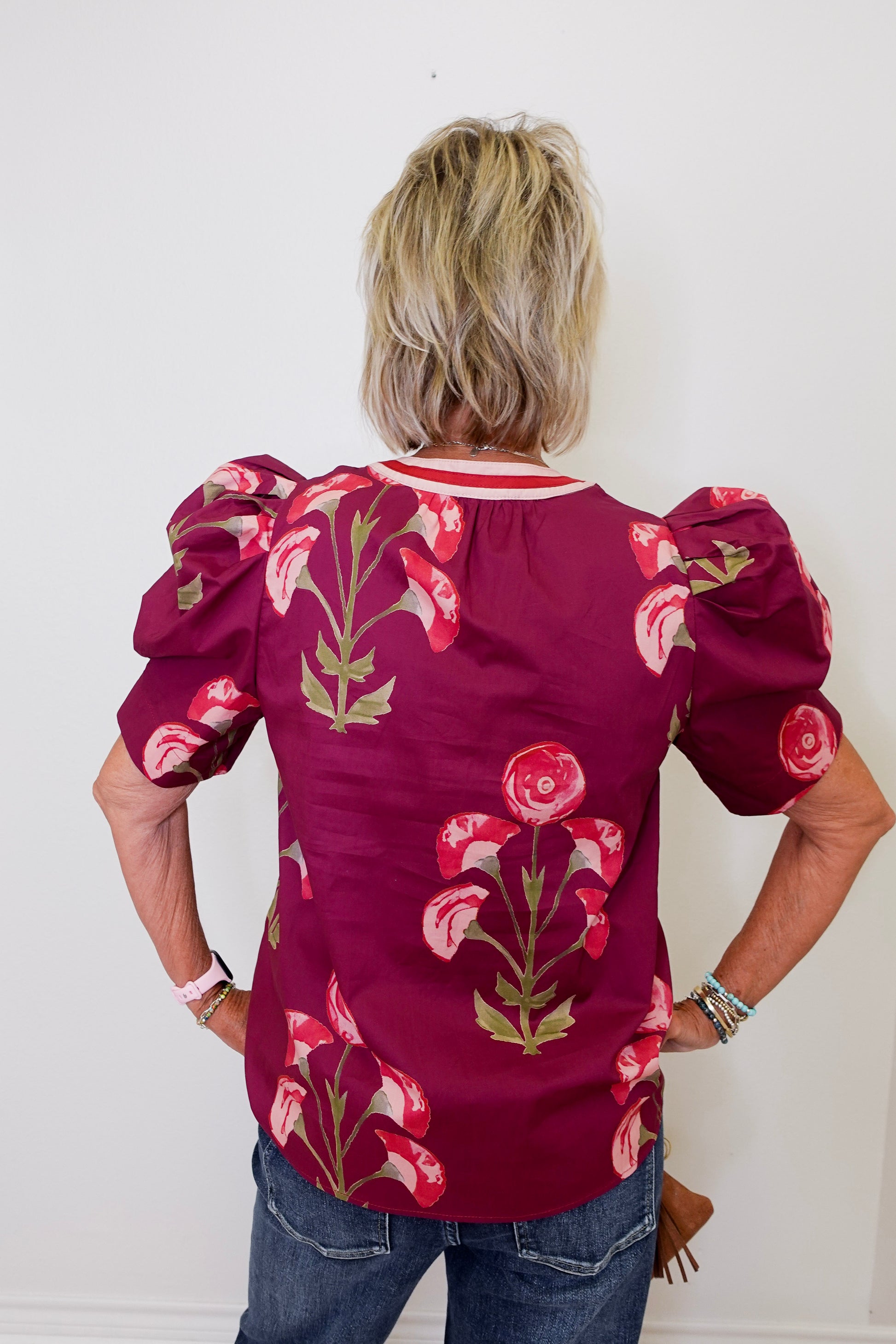 Person wearing a burgundy blouse with floral patterns against a white background