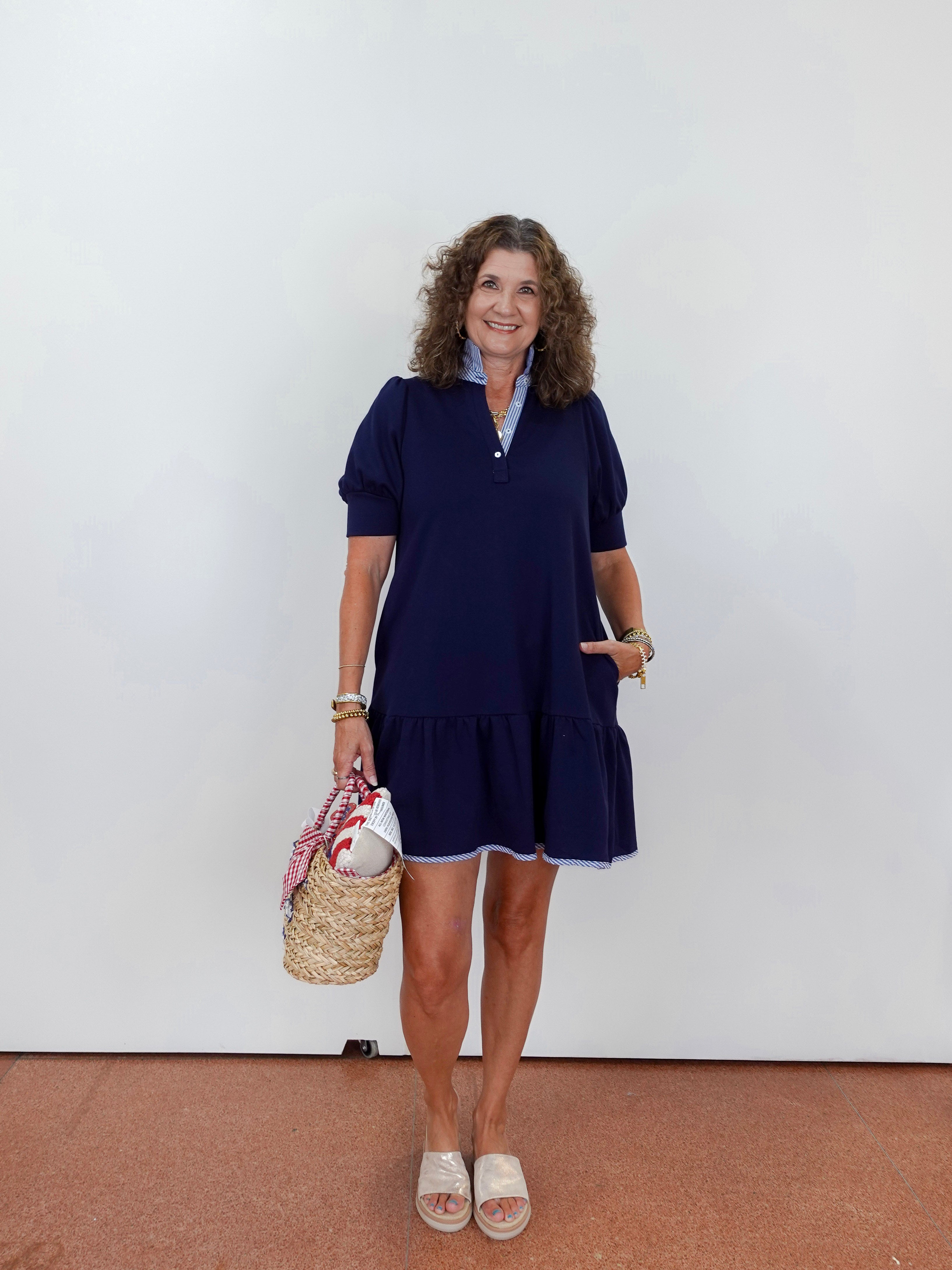 Woman wearing a navy dress with a white wall background