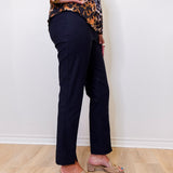 Person wearing a leopard print top and navy pants against a white wall.
