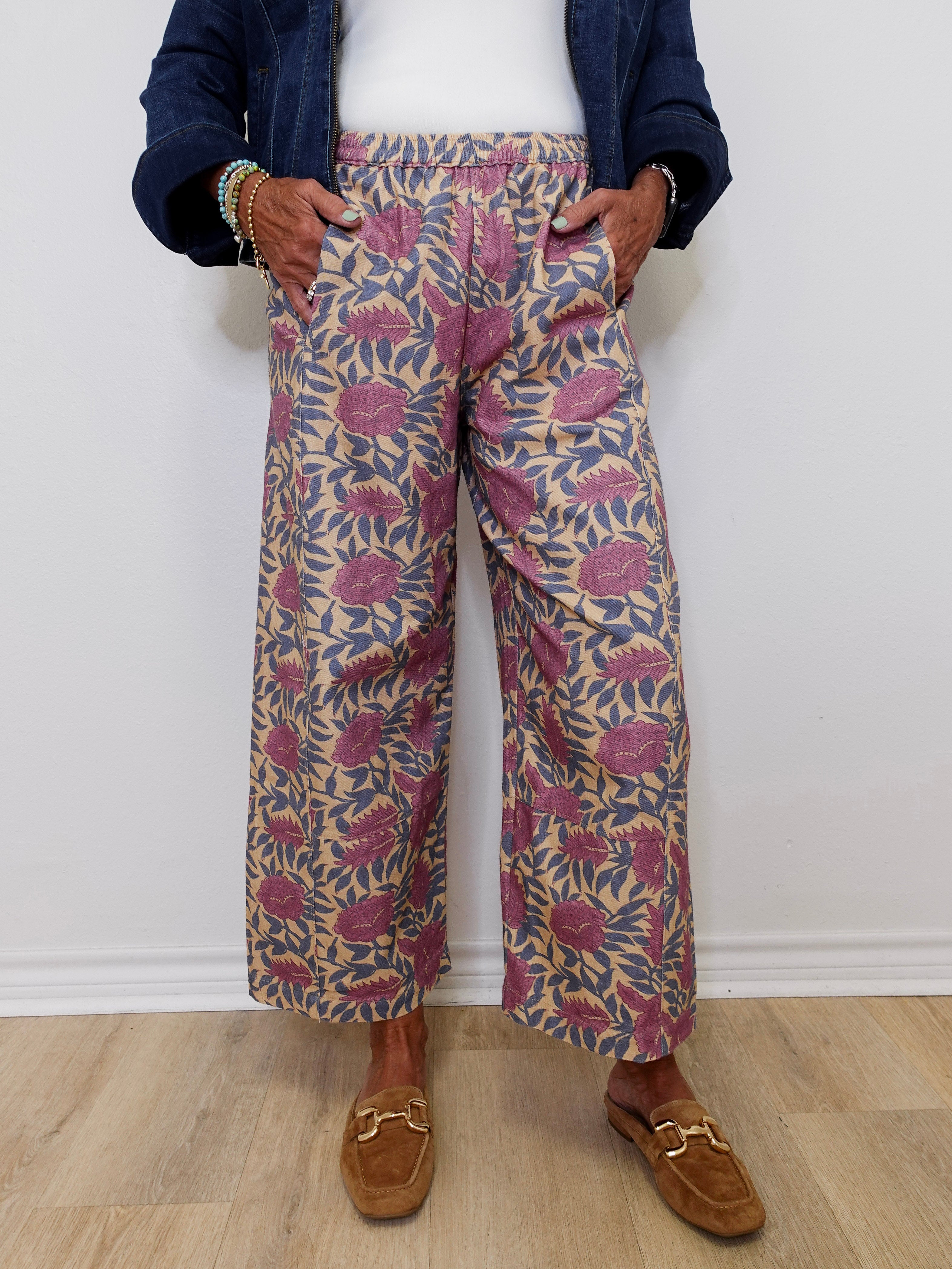 Person wearing patterned pants and brown loafers against a white wall.