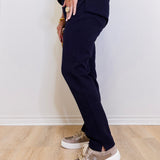 Person wearing navy blue pants and patterned sneakers on a light wooden floor.