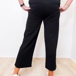 Person wearing black pants and white shoes on a light wooden floor.