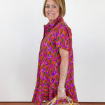 Woman wearing a colorful patterned dress holding a basket with beads on a plain background