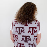 Person wearing a white letterman jacket with red and black 'ATM' logo on a plain background
