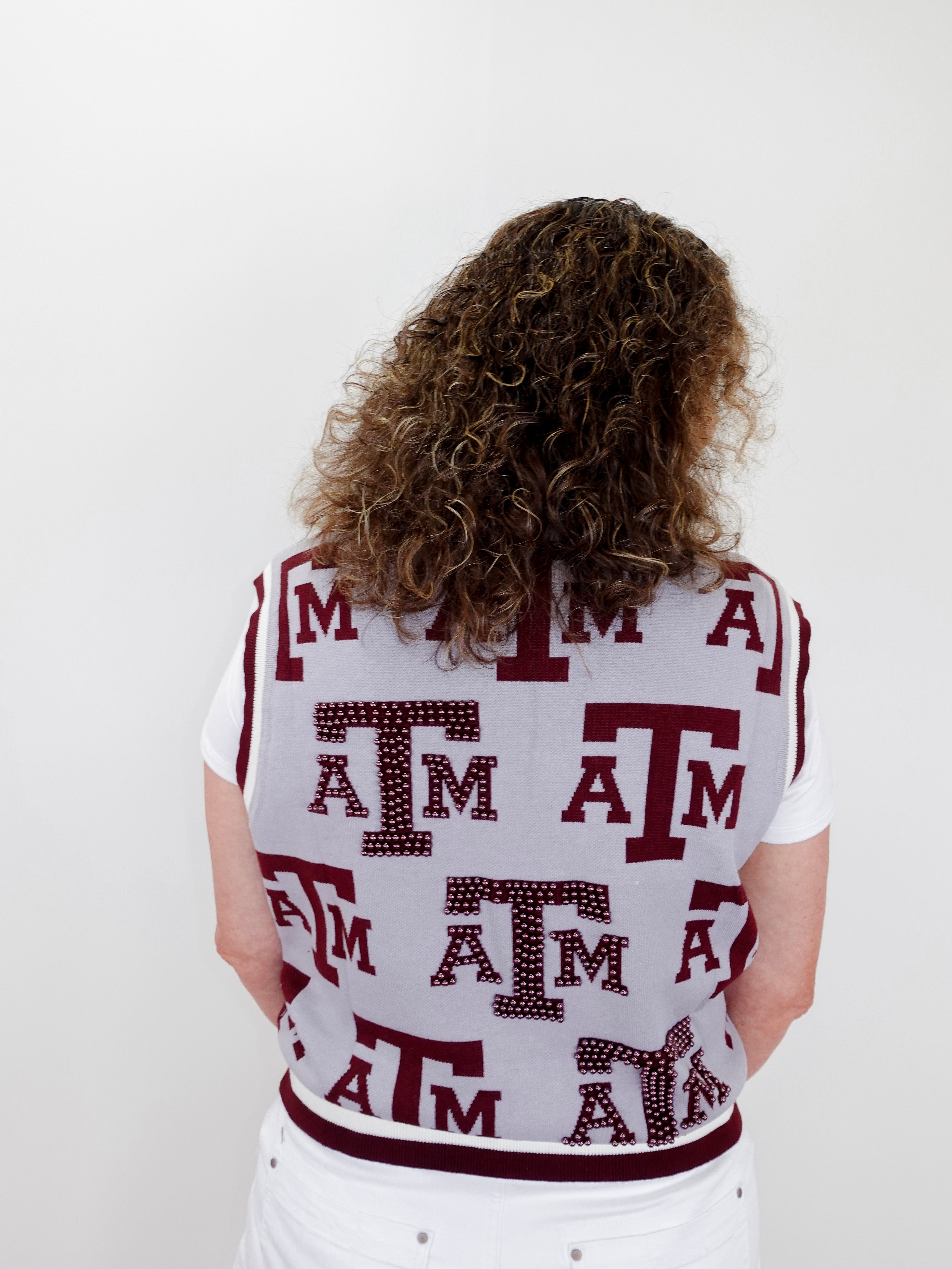 Person wearing a white letterman jacket with red and black 'ATM' logo on a plain background