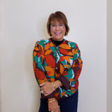 Woman wearing a colorful patterned shirt against a plain background