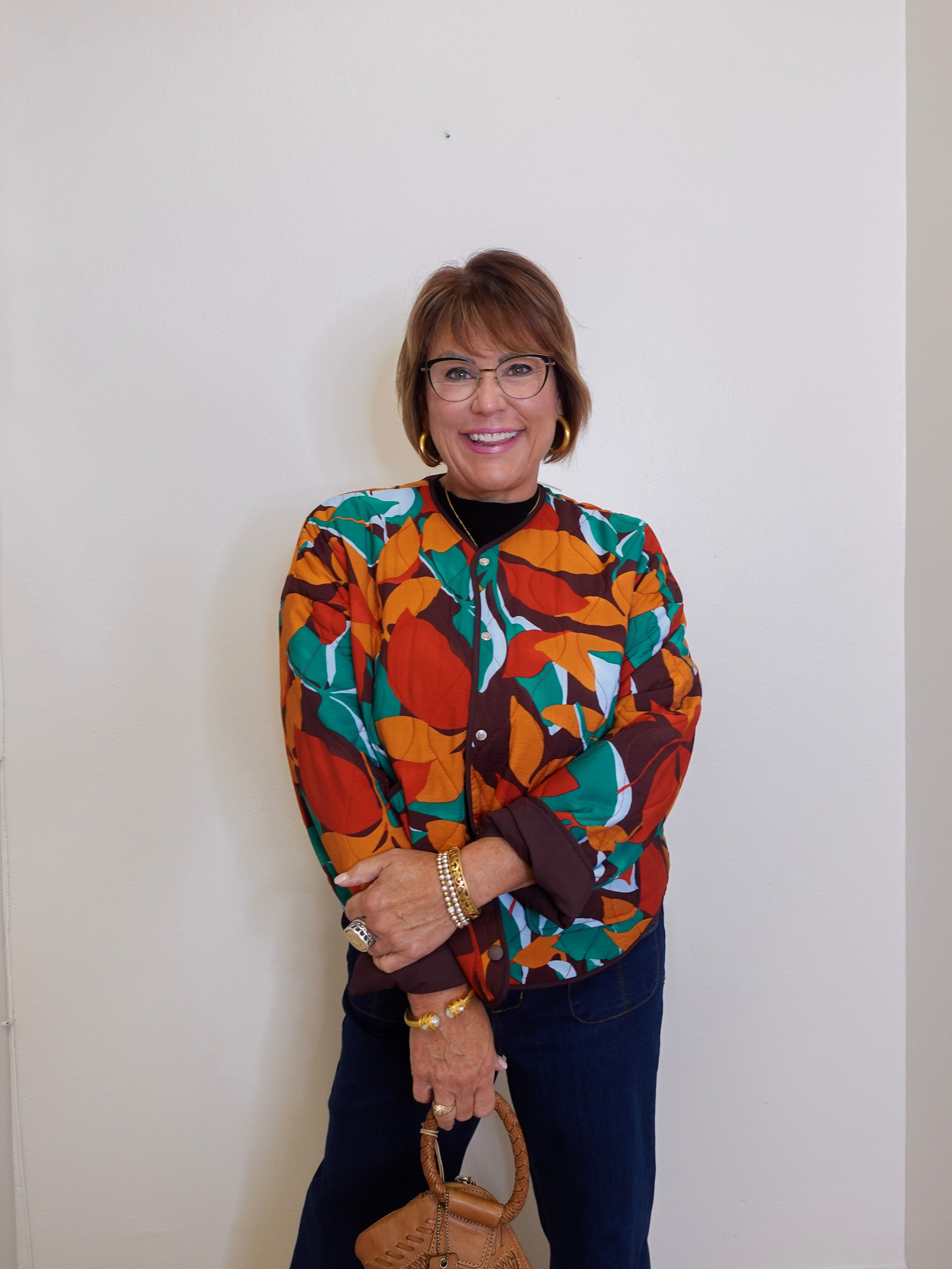 Woman wearing a colorful patterned shirt against a plain background