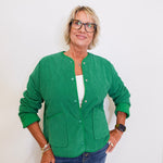 Woman wearing a green jacket and glasses against a white background