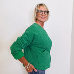 Woman wearing a green sweater and glasses against a white background