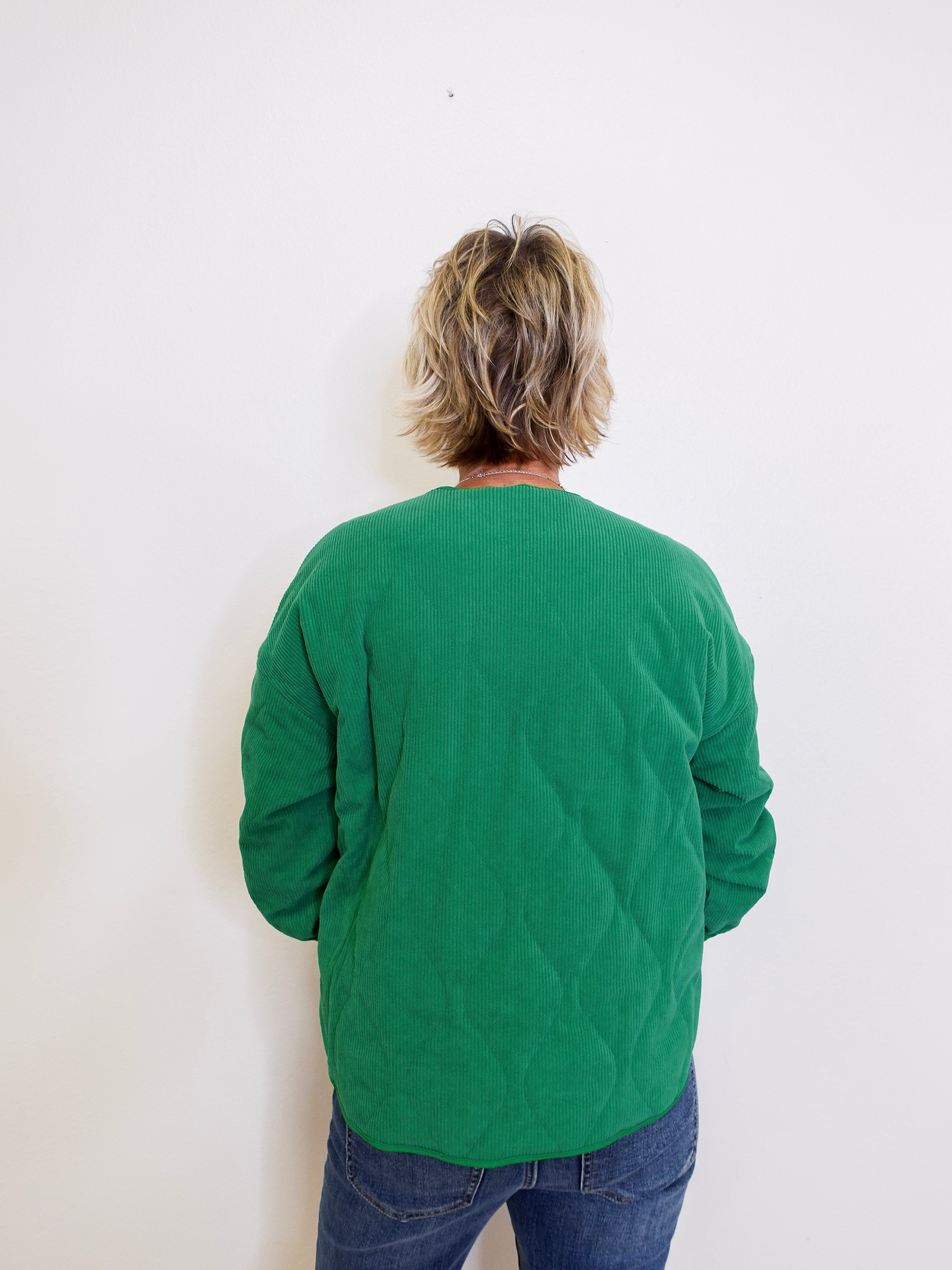 Person wearing a green sweater against a white background