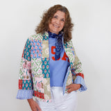 Woman wearing a colorful patchwork jacket over a blue shirt with red letters on a white background
