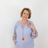 Woman wearing a light blue blouse with colorful sleeves against a white background