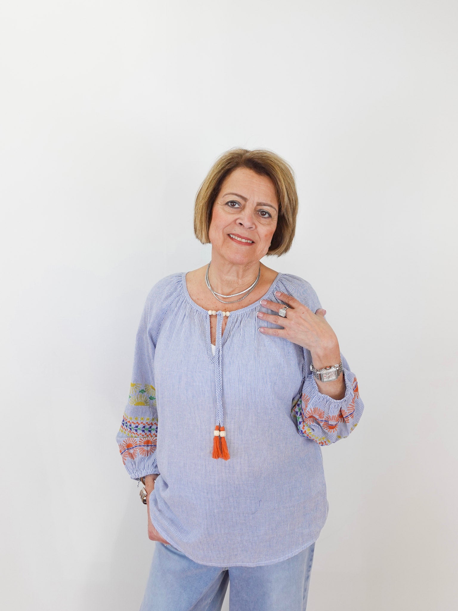 Woman wearing a light blue blouse with colorful sleeves against a white background